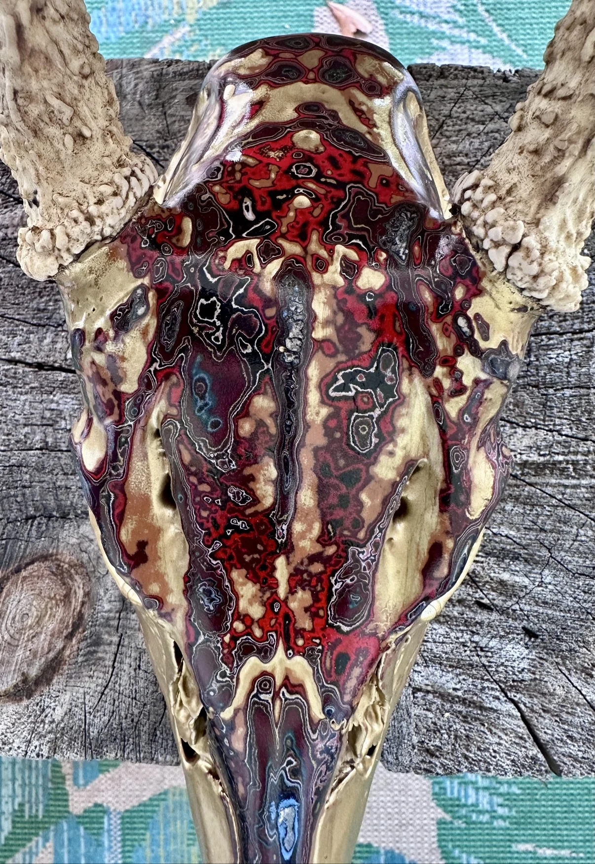 Close-up photograph of the top of my golden deer skull, showing the deep red, gold and black swirls of the layered fordite finish